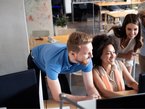 Inclusive team of 4 people collaborating on a desktop computer in a modern office